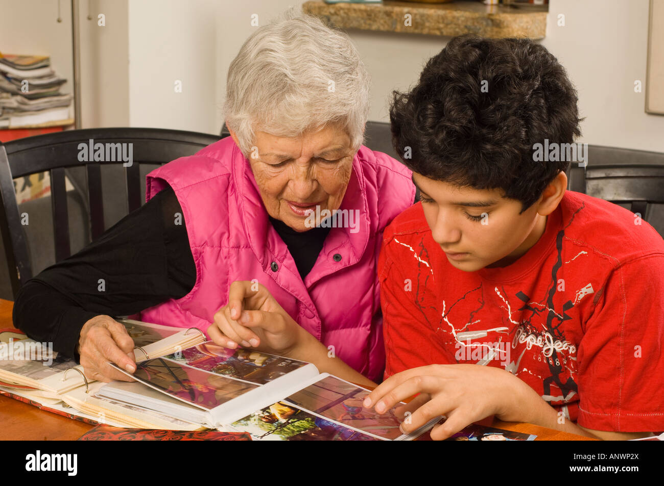 Mujer Senior abuela mirando fotografías en álbumes de familia con adolescentes de 13 años nieto vertical Foto de stock