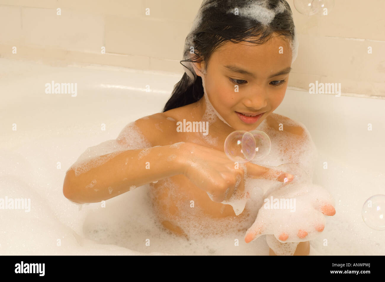 Niña de 7 años jugando en baño de burbujas asiático americano Vietnamita Foto de stock