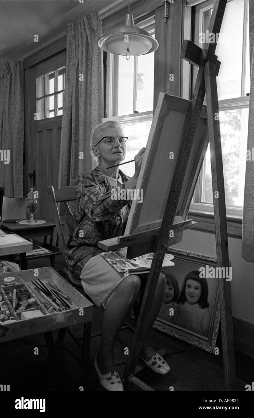 Una mujer de 70 años, quien tomó posesión de la pintura después de la jubilación trabaja en un retrato Foto de stock