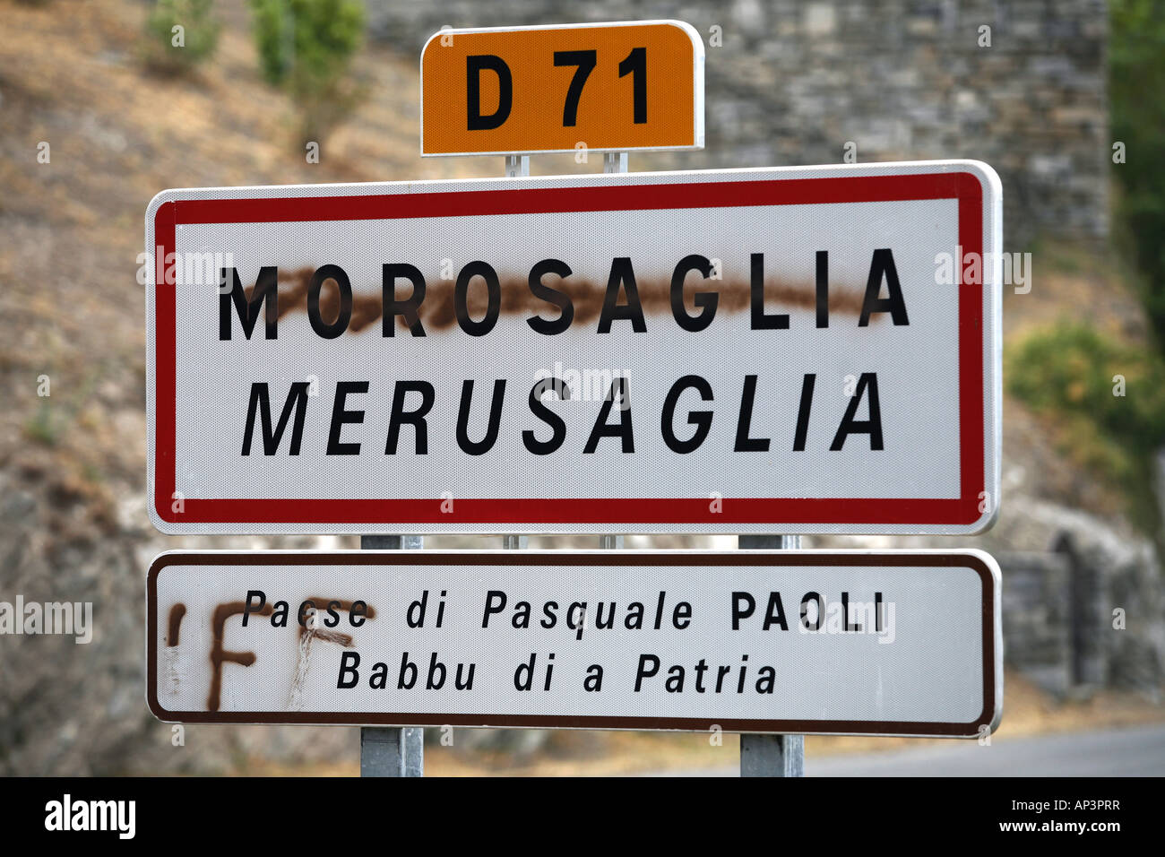Señal de carretera bilingües con nombres franceses tachado, Morosaglia, Córcega, Francia Foto de stock