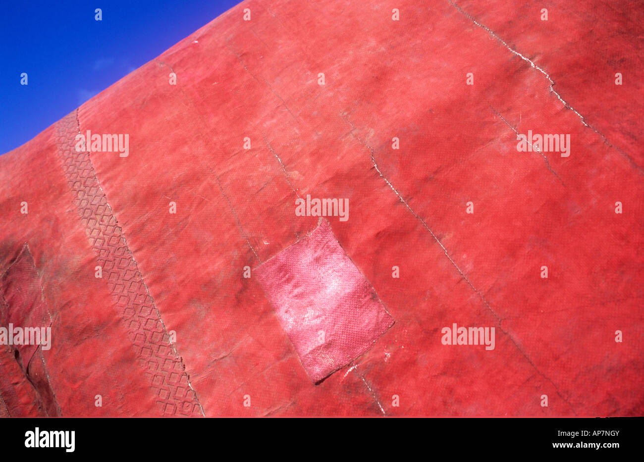 Detalle de plástico rojo sucio o lona de nylon de color rojo pálido con  hoja de reparación y con un triángulo de cielo azul profundo Fotografía de  stock - Alamy