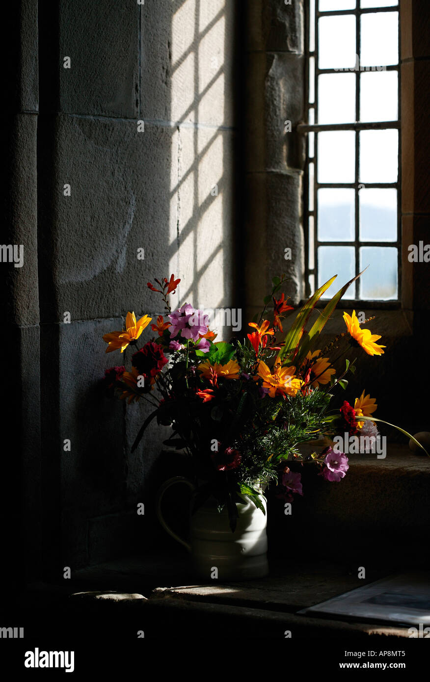 Sigue la vida de un jarrón de flores de colores en Abbey, isla de Iona, Escocia con sombra de cristal plomado Foto de stock