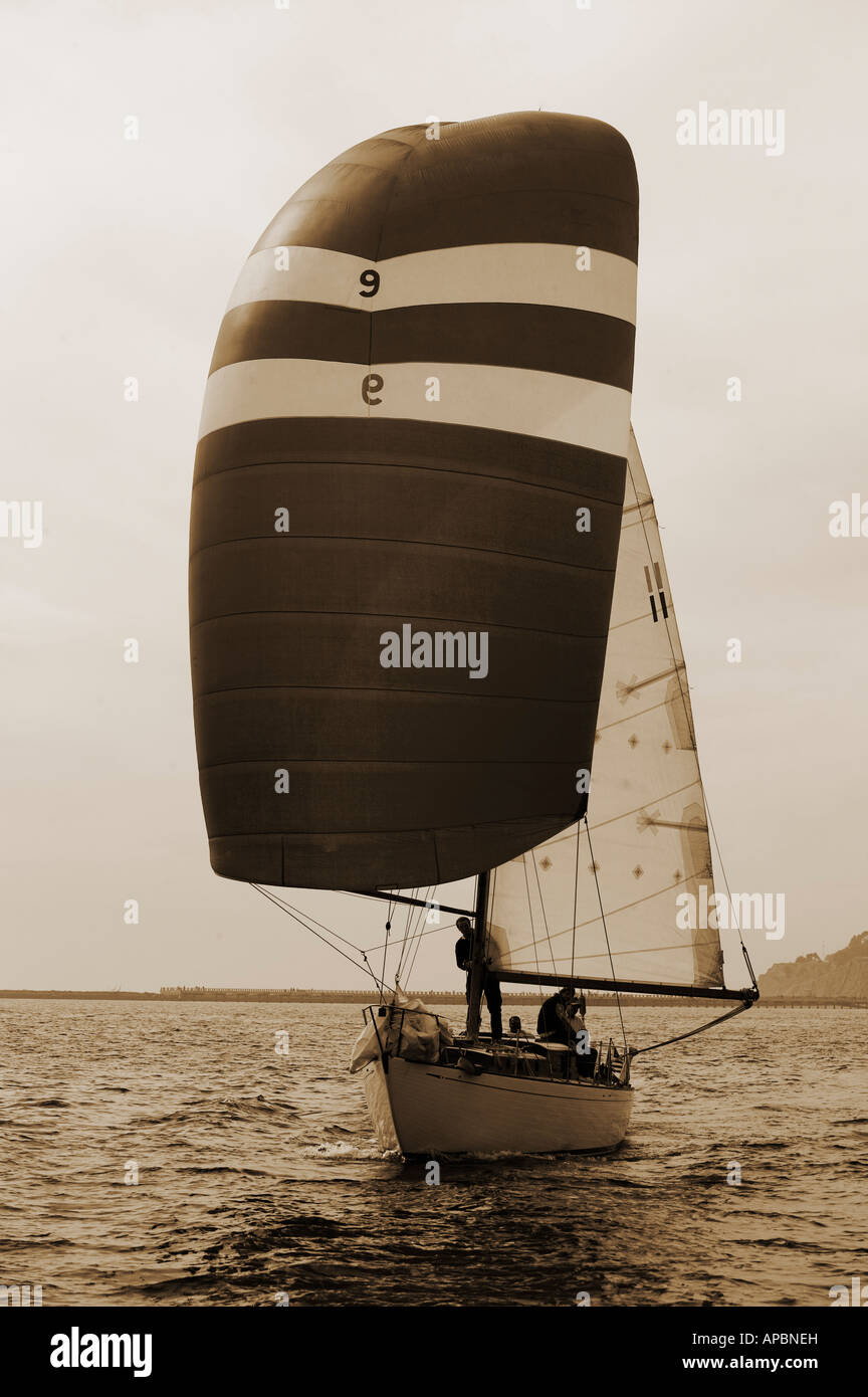 Velero de crucero en tonos sepia blanco y negro viaje Viajes Vacaciones de aventura raza spinnaker mar en calma brisa ligera viento Foto de stock
