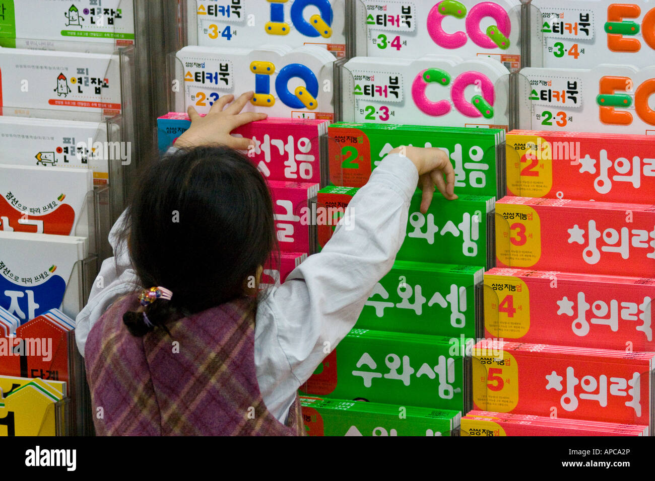 Joven chica coreana Reaching for Educational Book en una librería Seúl, Corea del Sur Foto de stock