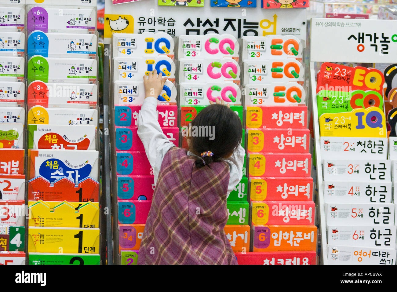 Joven chica coreana Reaching for Educational Book en una librería Seúl, Corea del Sur Foto de stock