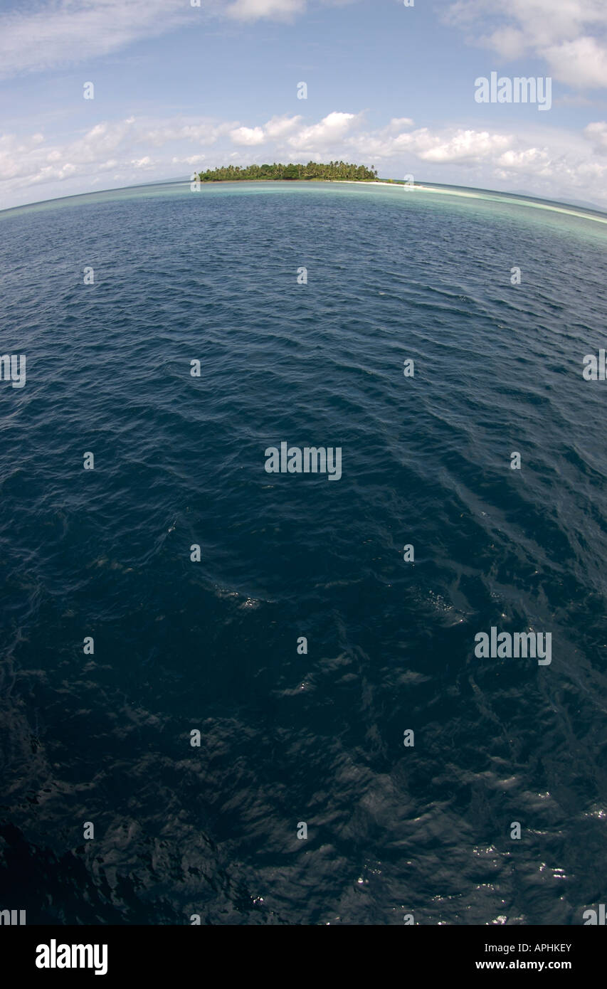 Un islote de coral aislados se asienta sobre una curvatura vista del océano Foto de stock