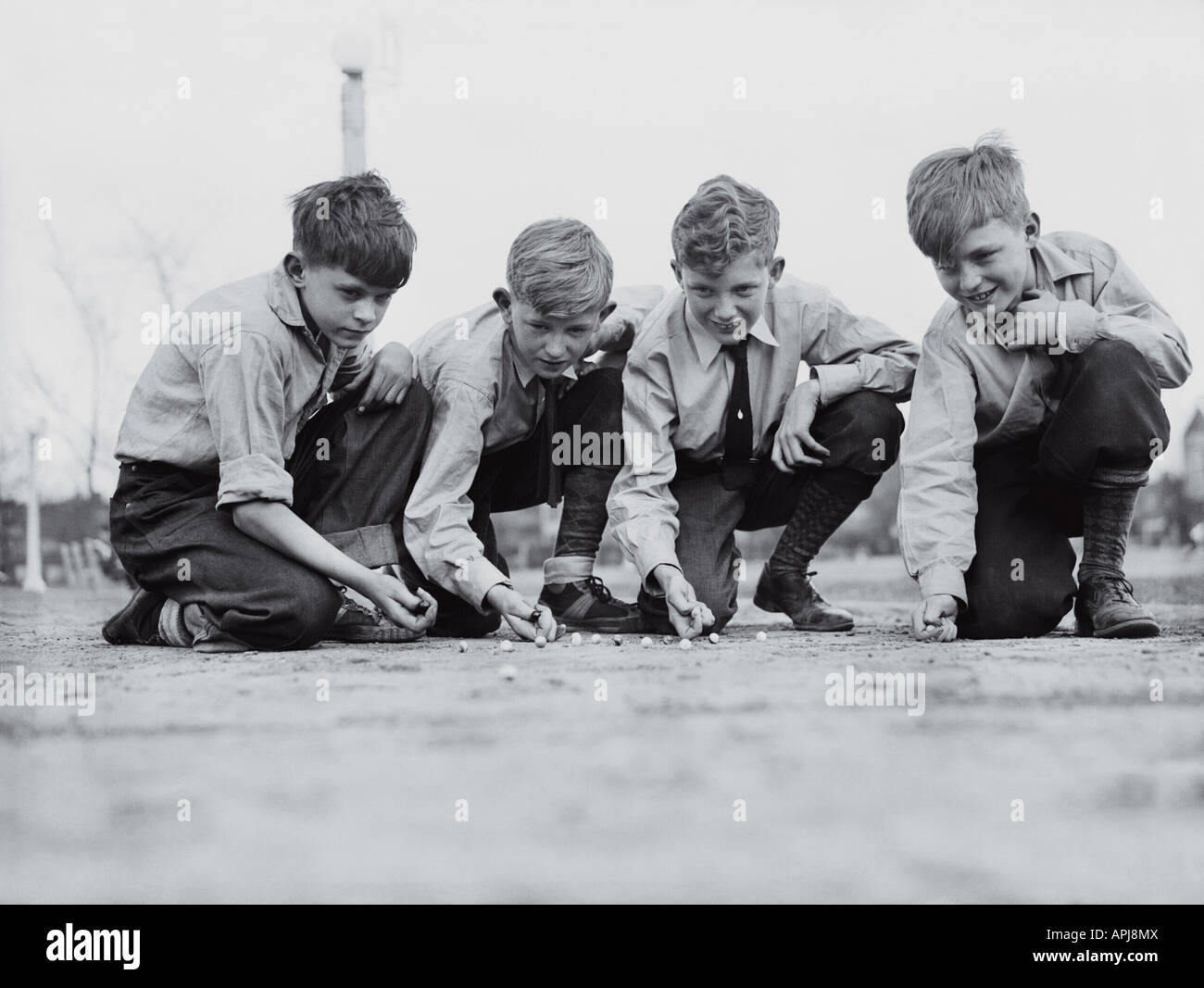 Cuatro muchachos jugando a las canicas en Chase Park, Chicago, Illinois. El 29 de abril de 1939. Foto de stock