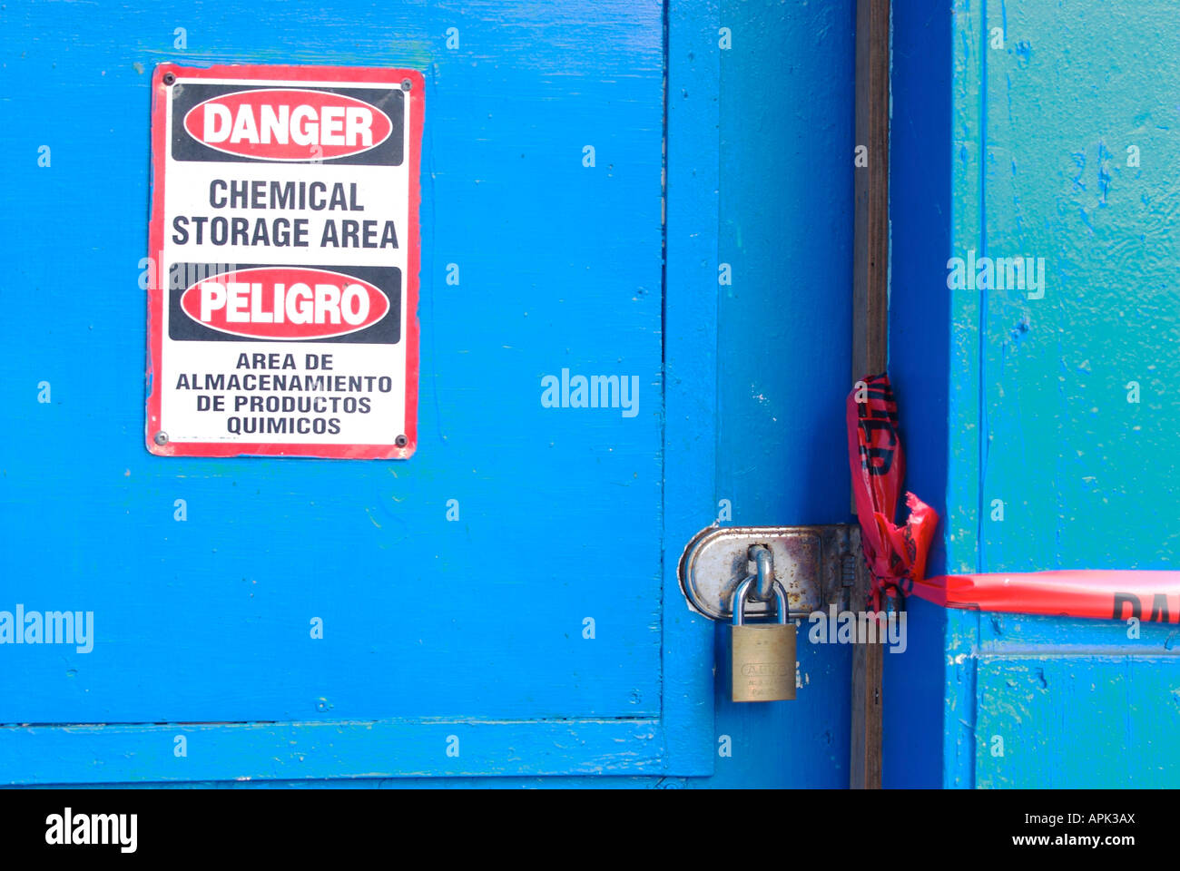Portada azul saturado con señal de peligro para el almacenamiento de productos químicos (en inglés y español Foto de stock