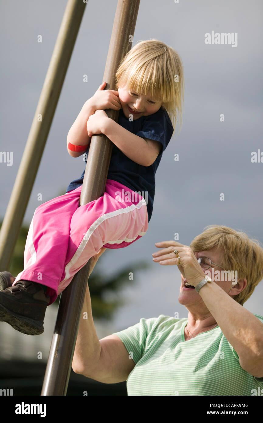 Niña de 4 años Bajando un puesto en un parque con la Abuela Foto de stock