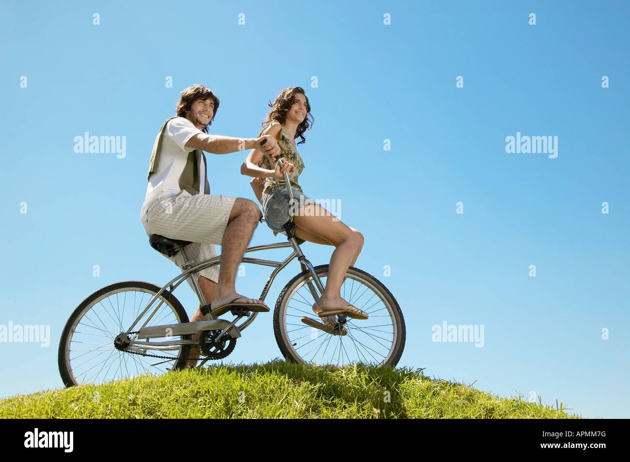 Pareja joven en bicicleta por Hill (ángulo de visión baja) Foto de stock