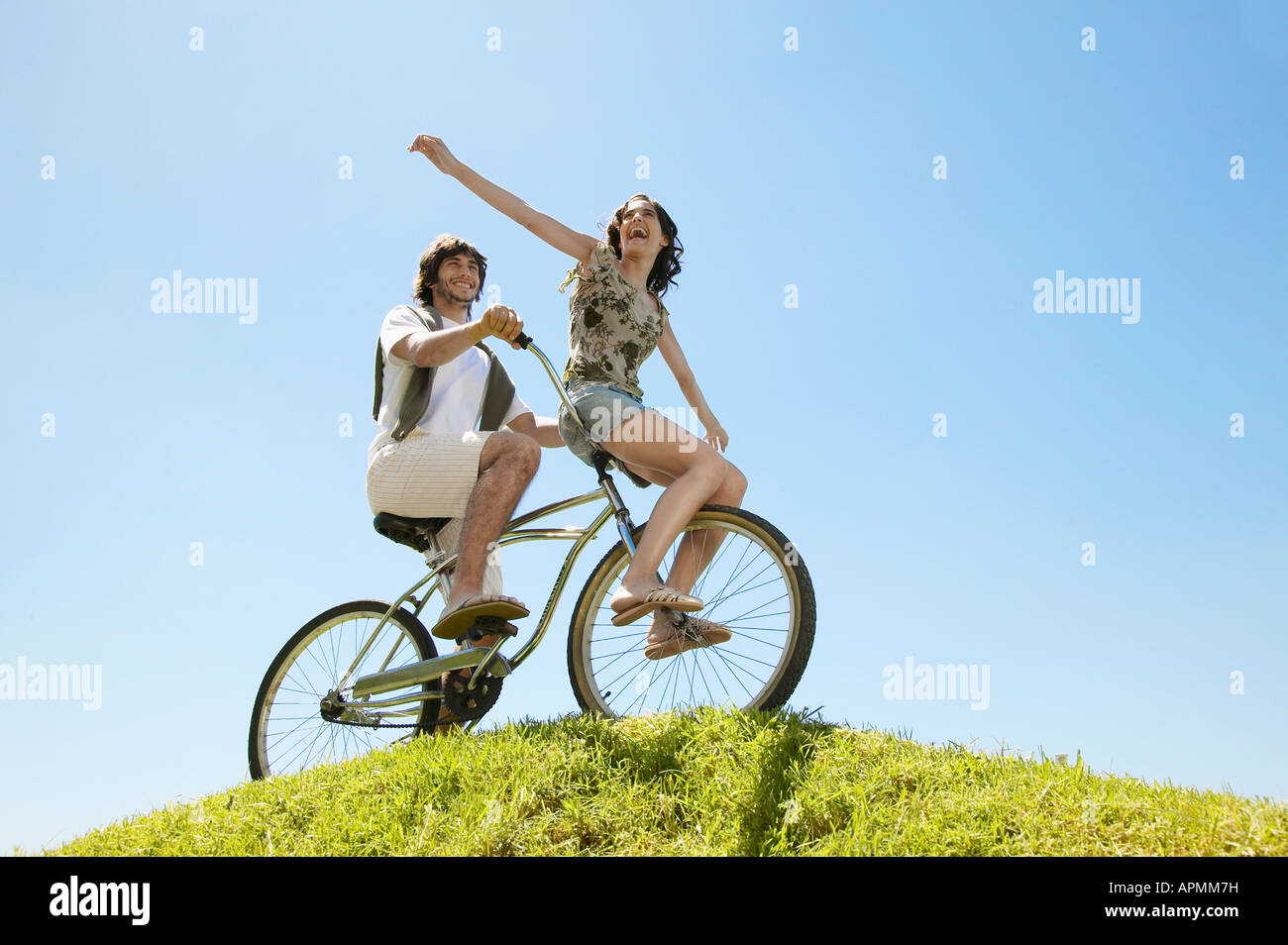 Pareja joven en bicicleta por Hill (ángulo de visión baja) Foto de stock