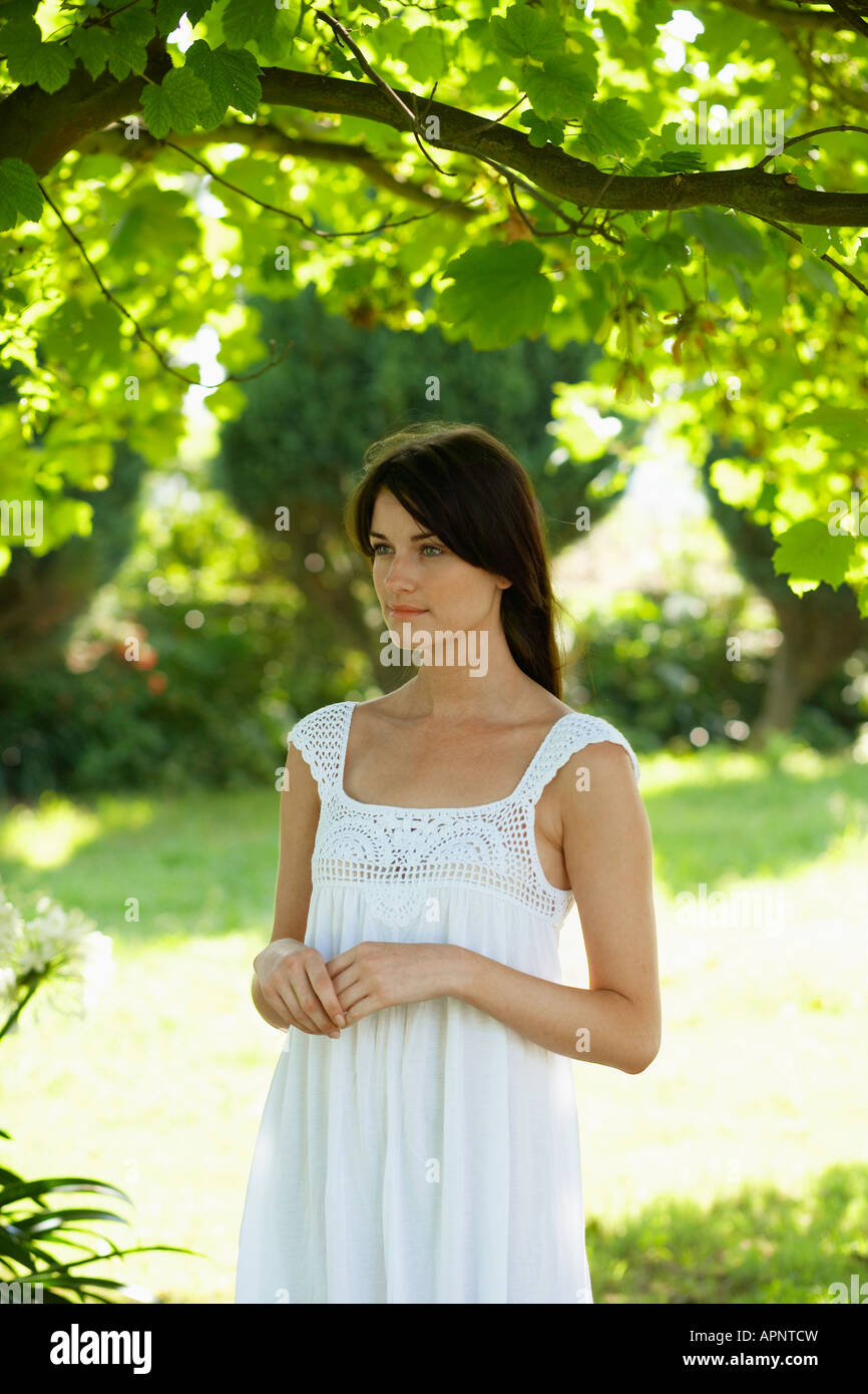 Mujer joven vestido vestidos de blanco en el jardín Foto de stock