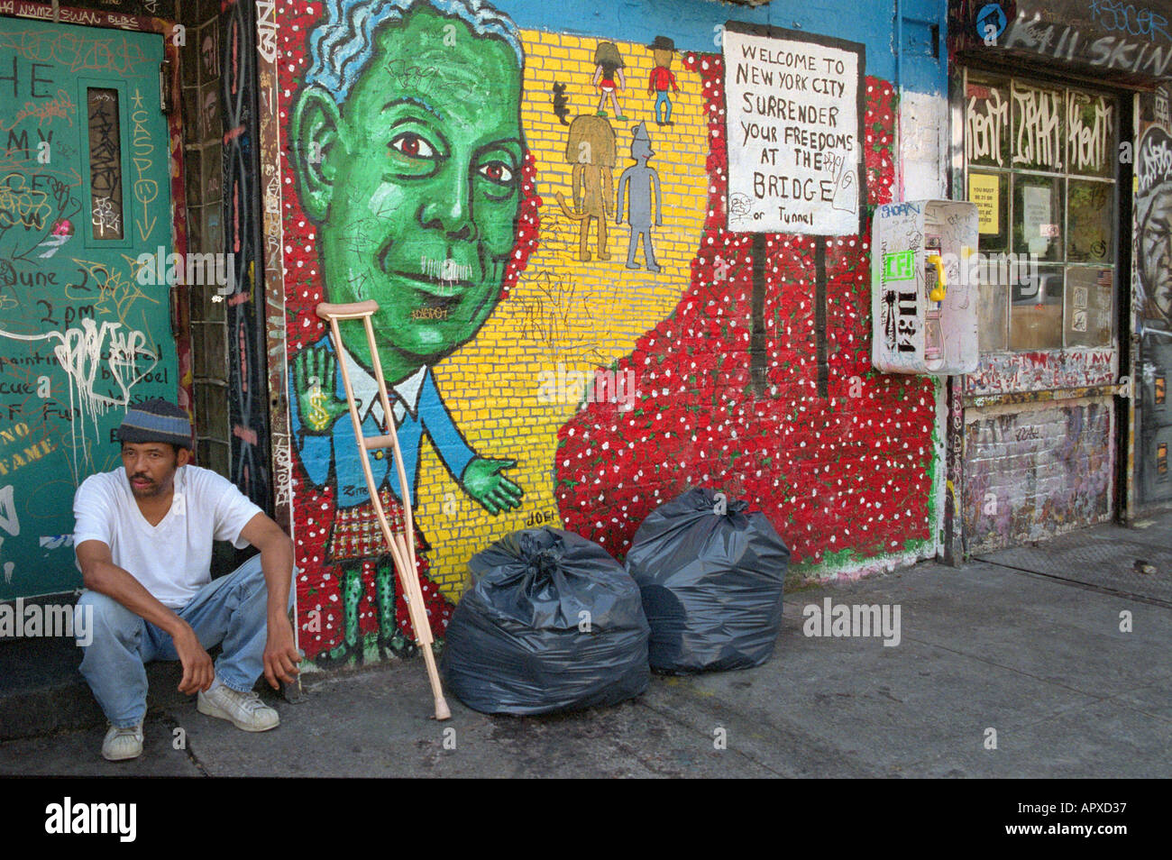 Personas sin hogar hombre sentado contra la pared de graffiti en El Manhattans Eastside inferior. Foto de stock