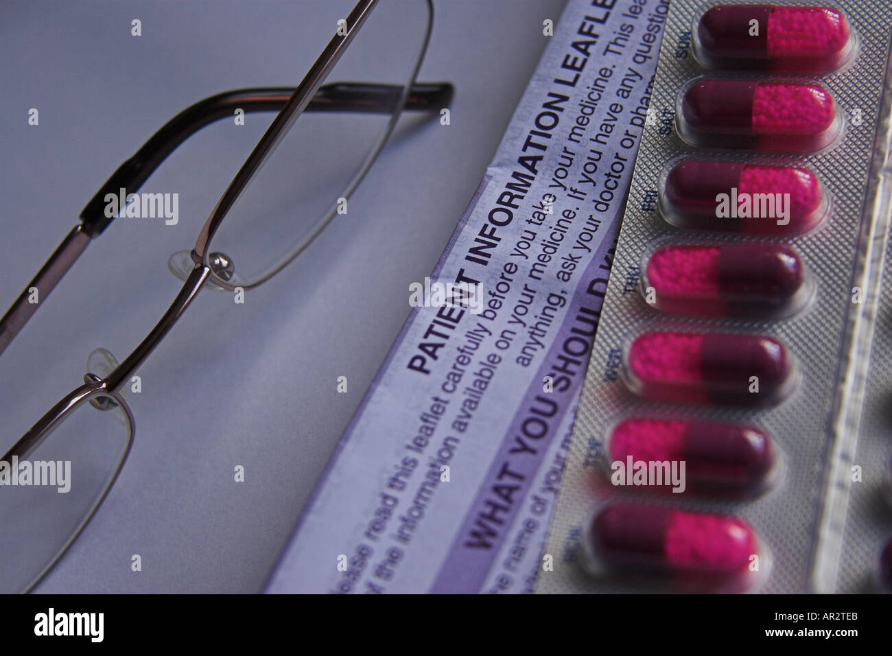 Concepto imagen mostrando tabletas medicinales / píldoras / cápsulas, gafas de lectura y folleto de información sobre el medicamento. Foto de stock