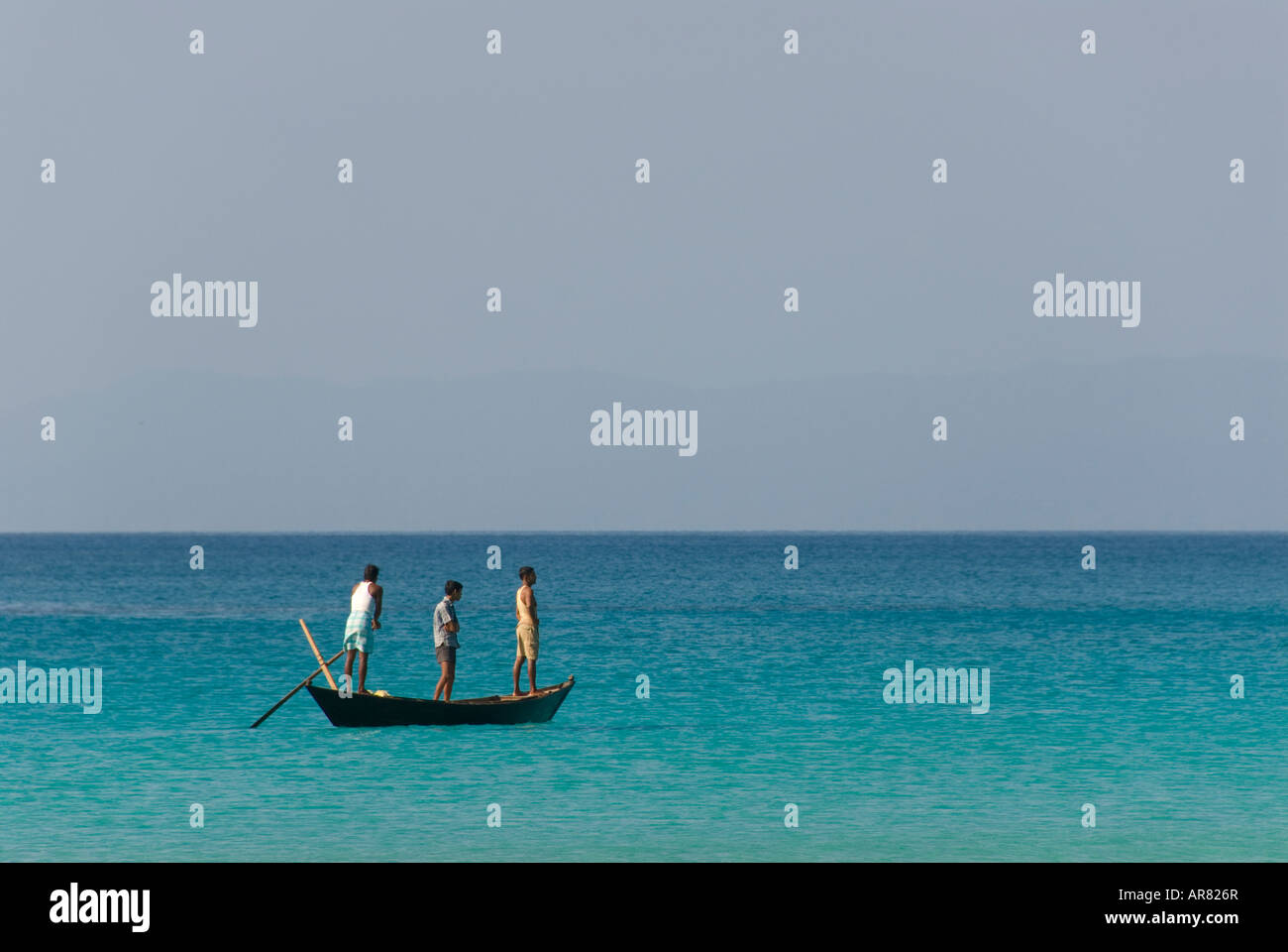 Tres hombres en un barco en el mar en la India Foto de stock