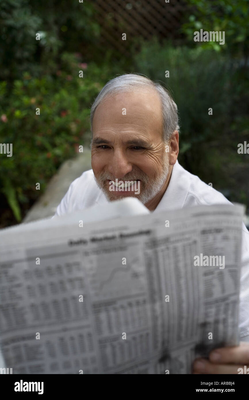Hombre leyendo el periódico en el exterior Foto de stock