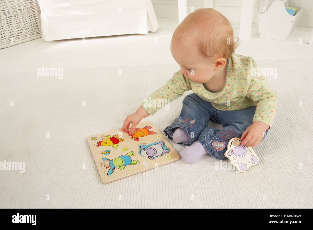 Un bebé se sienta en el suelo y juega con un puzzle de formas de madera  Fotografía de stock - Alamy