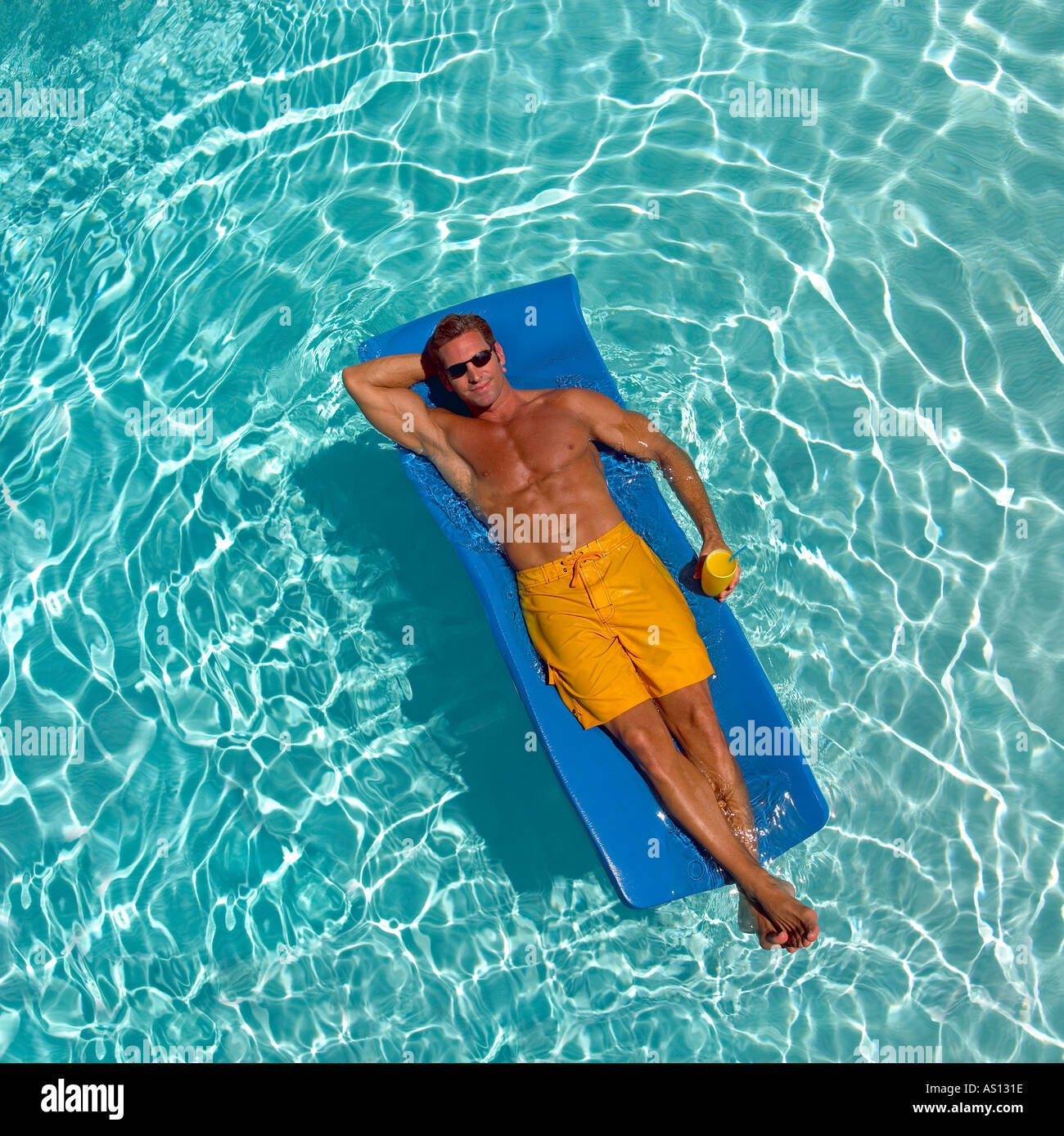 Fotografía cenital del hombre en amarillo bañadores gafas de sol en  brillante azul verde azul piscina en balsa los brazos sobre la cabeza  sonriendo Fotografía de stock - Alamy