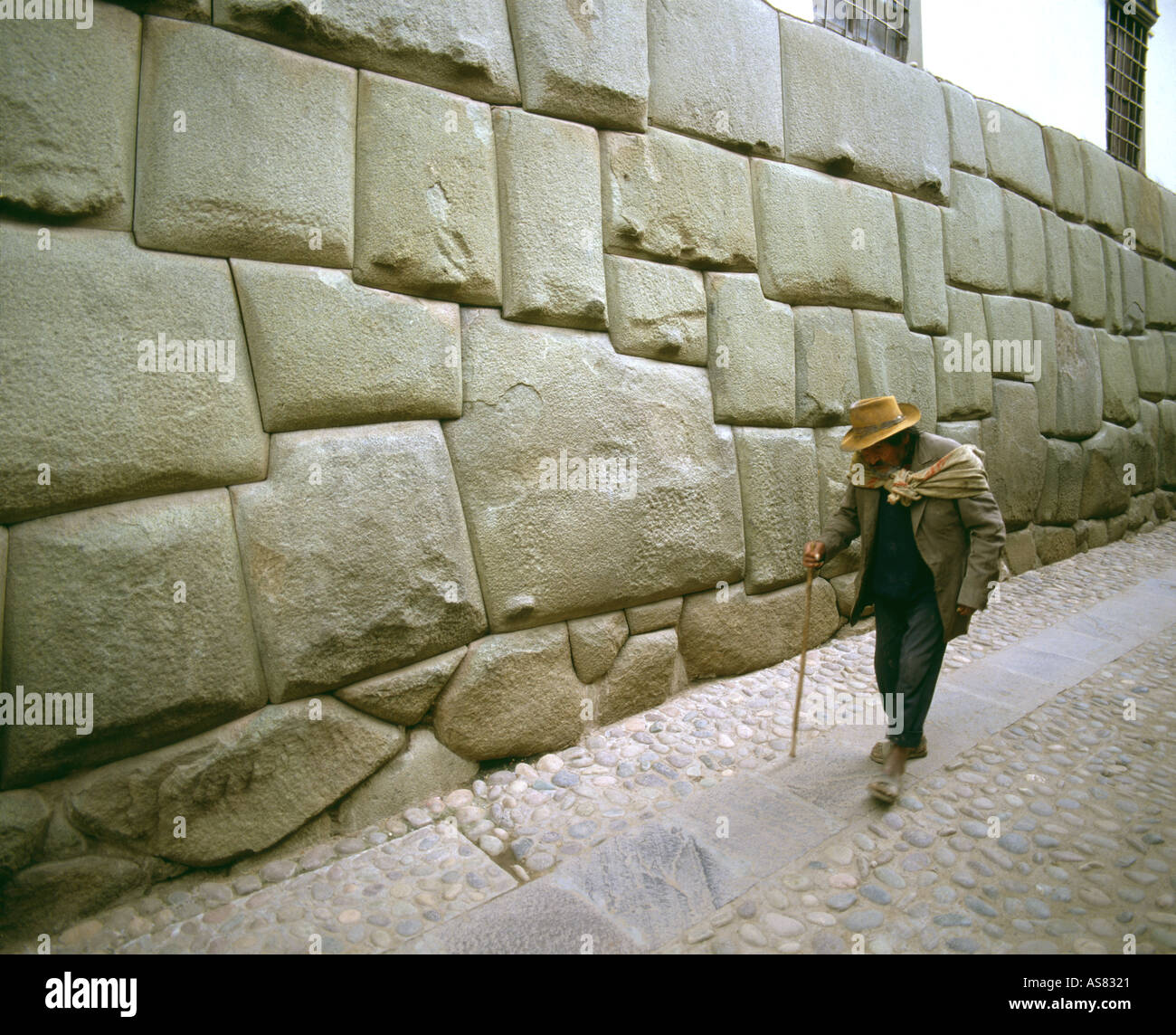 En sandalias hombre quechua local pasando la piedra de los doce ángulos  fijados en muro inca original en la calle Cuzco Perú Fotografía de stock -  Alamy