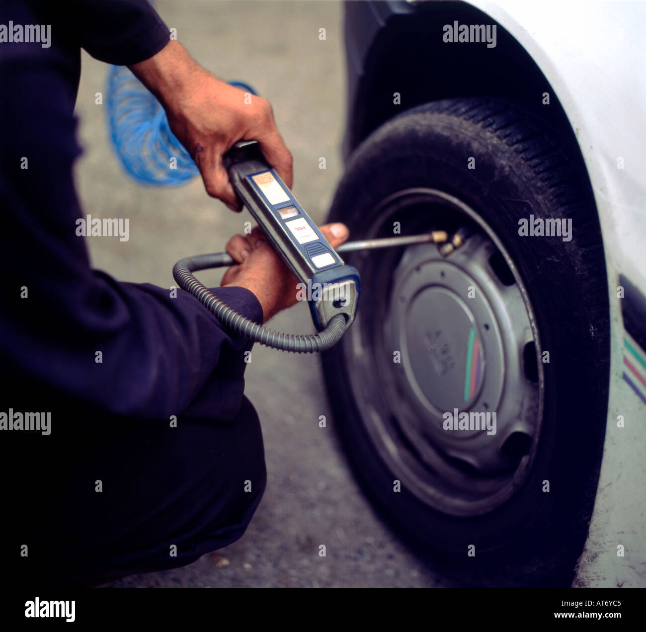 Hombre sujetando un manómetro y introduciendo aire en los neumáticos Gales UK KATHY DEWITT Foto de stock