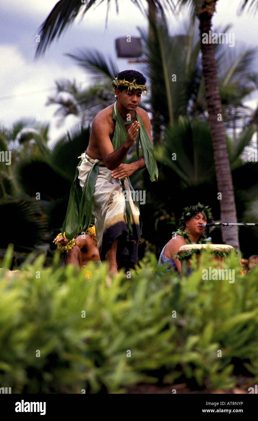 Apuesto joven hombre hawaiano, vistiendo un traje de hula tradicional con hojas de ti y tapa, cierra los ojos y evoca un humor sagrado Foto de stock