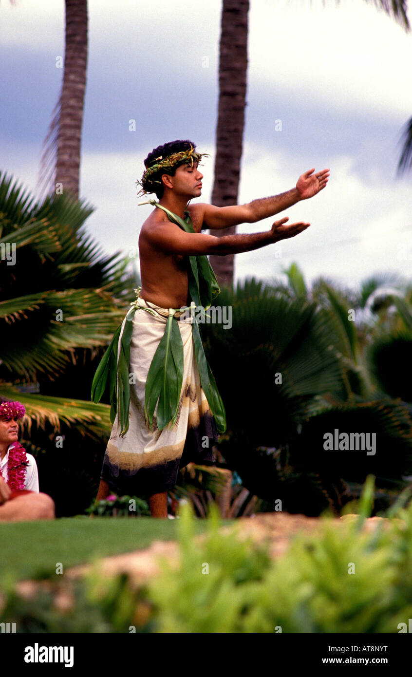 Apuesto joven hombre hawaiano, vistiendo un traje de hula tradicional con hojas de ti y tapa, cierra los ojos y evoca un humor sagrado Foto de stock