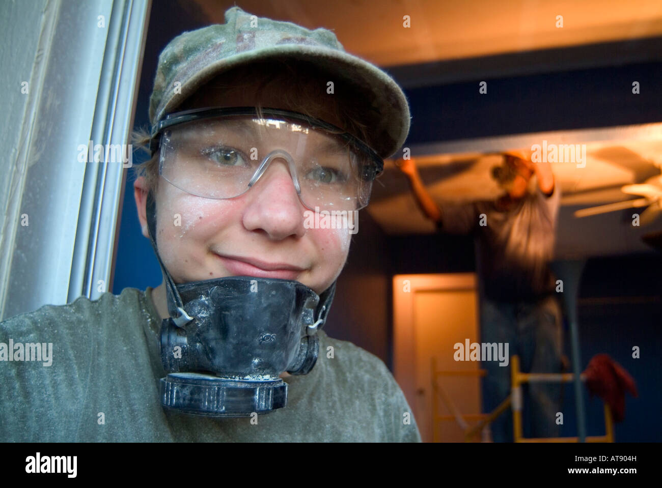 Inicio Los trabajos de construcción. Adolescente llevaba una máscara ventalation mientras ayudan a raspar el techo con antiguos hombre afroamericano Foto de stock