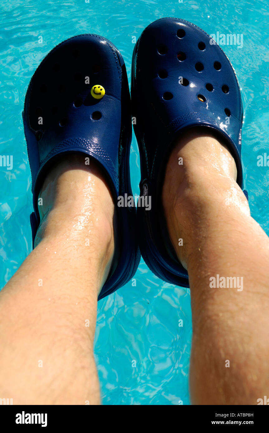 Crocs calzado playa azul piscina flotando zapatos para vacaciones par horizontal de color azul pies piernas macho Fotografía de stock - Alamy