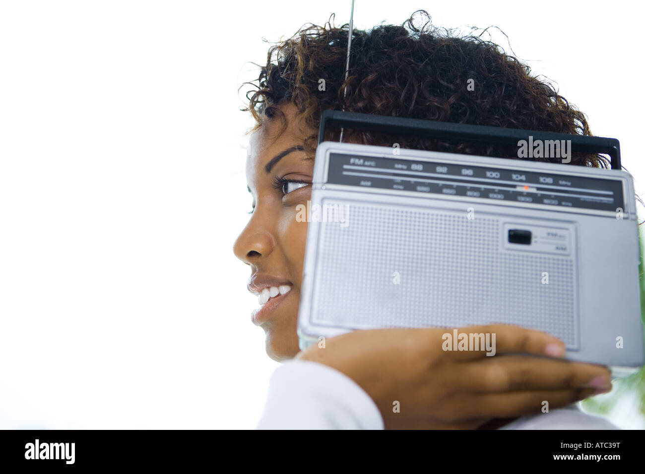Mujer sosteniendo radio junto al oído, sonriendo, vista lateral Foto de stock