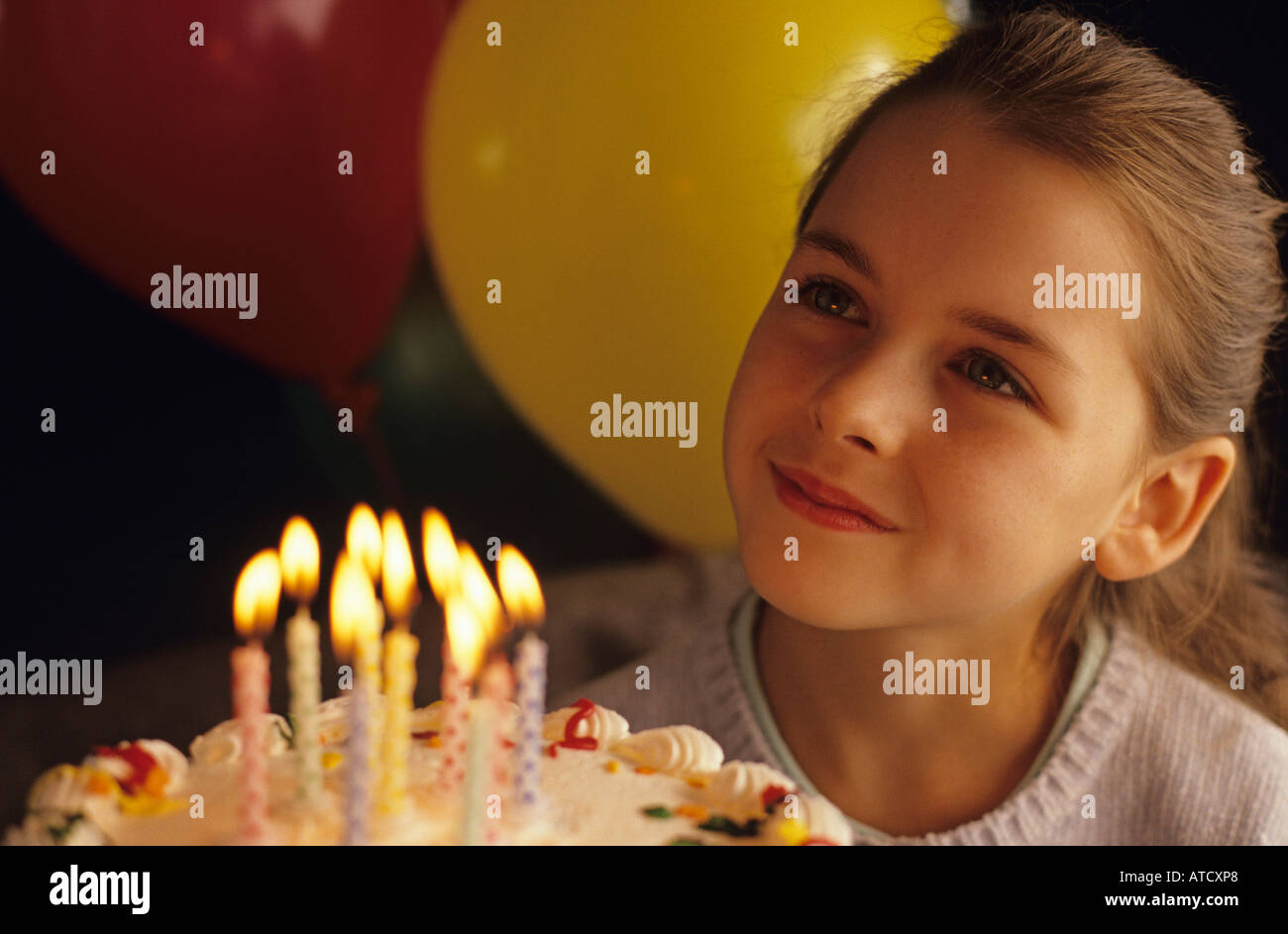Globos de colores con 9 años de edad, niña celebrando un cumpleaños con  tarta y velas luz cálida sobre rostro sonriente señor Fotografía de stock -  Alamy