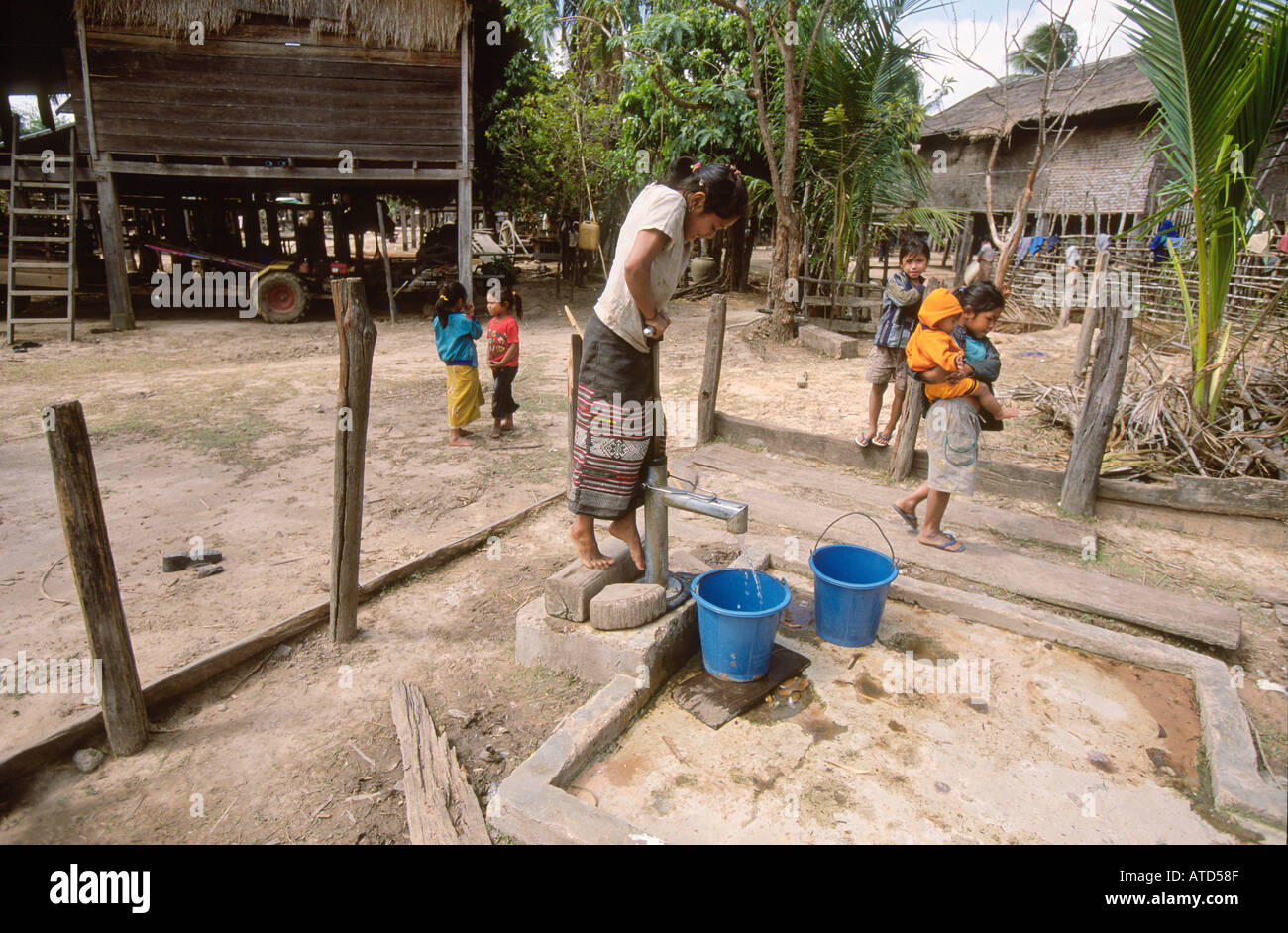 Niña recogiendo agua en el tubo de soporte en la remota aldea en el sur de Laos Foto de stock