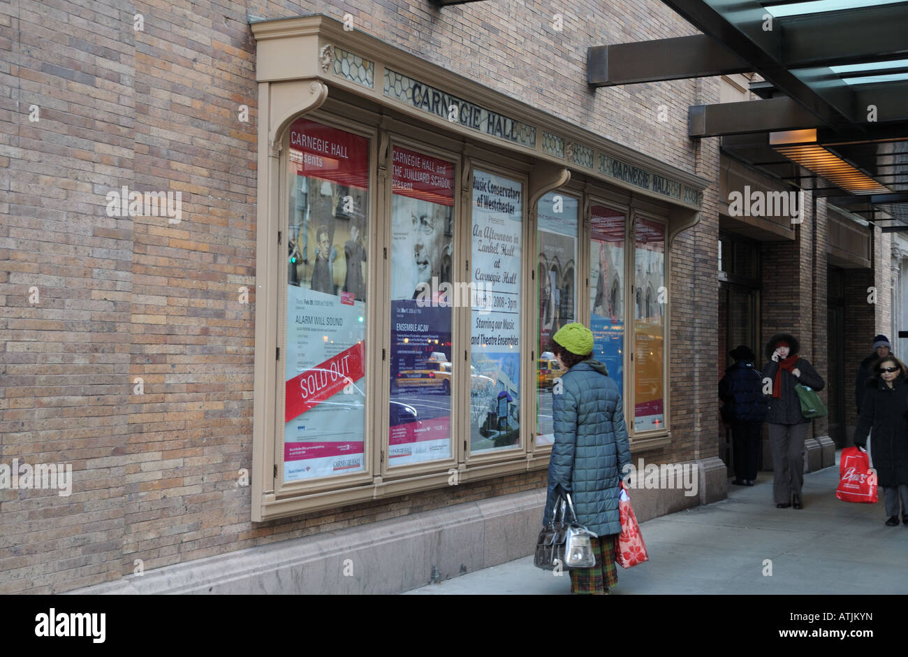 Una mujer lee anuncios para los próximos conciertos en el exterior de la ciudad de Nueva York el famoso Carnegie Hall. Foto de stock