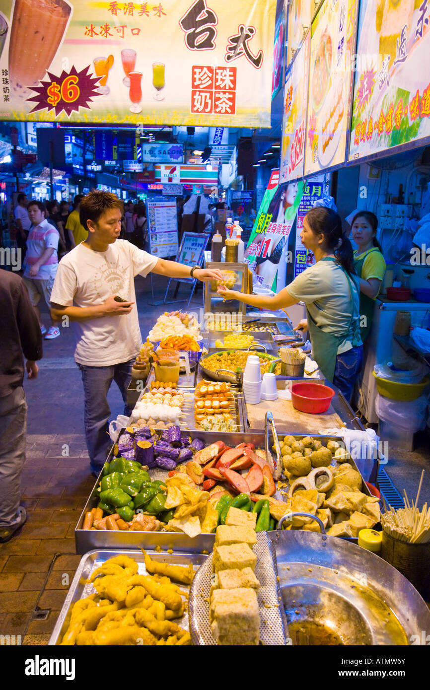 Vendedor de comida china de Hong Kong sobre la acera en la noche en el ajetreado barrio de Mong Kok en Kowloon Foto de stock