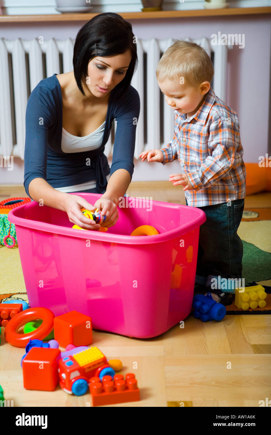 Mujer joven con baby boy durante la mujer plaing mostrando juguete para  bebé están en contenedor con juguetes vista frontal Fotografía de stock -  Alamy