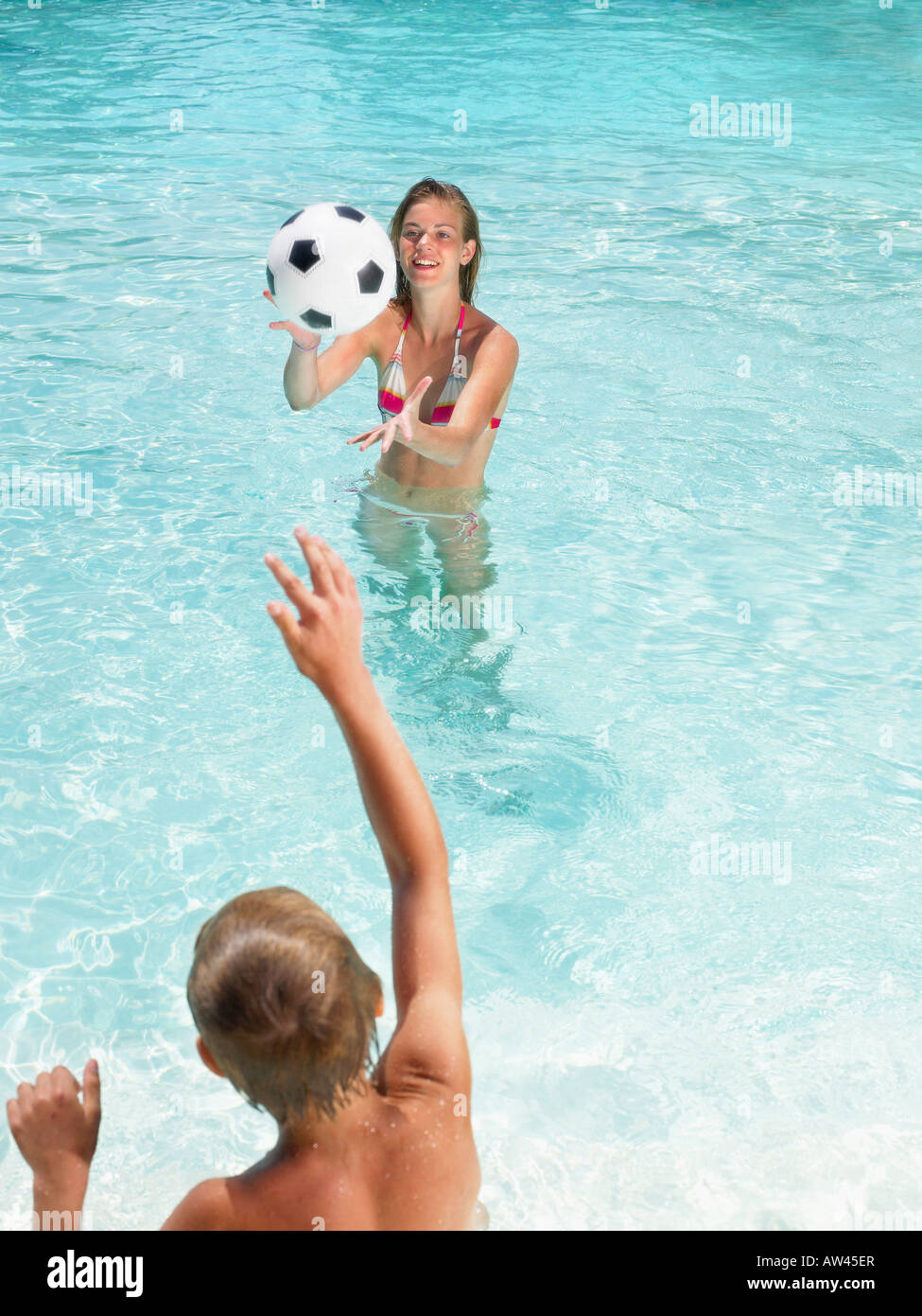Niños jugando con una pelota en la piscina. Foto de stock