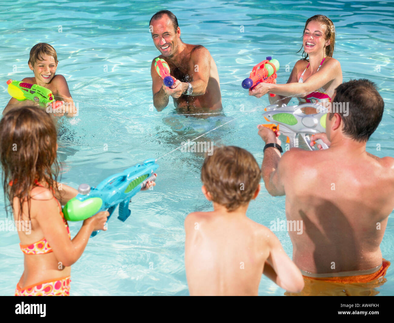 Niños y adultos jugando con pistolas de agua. Foto de stock