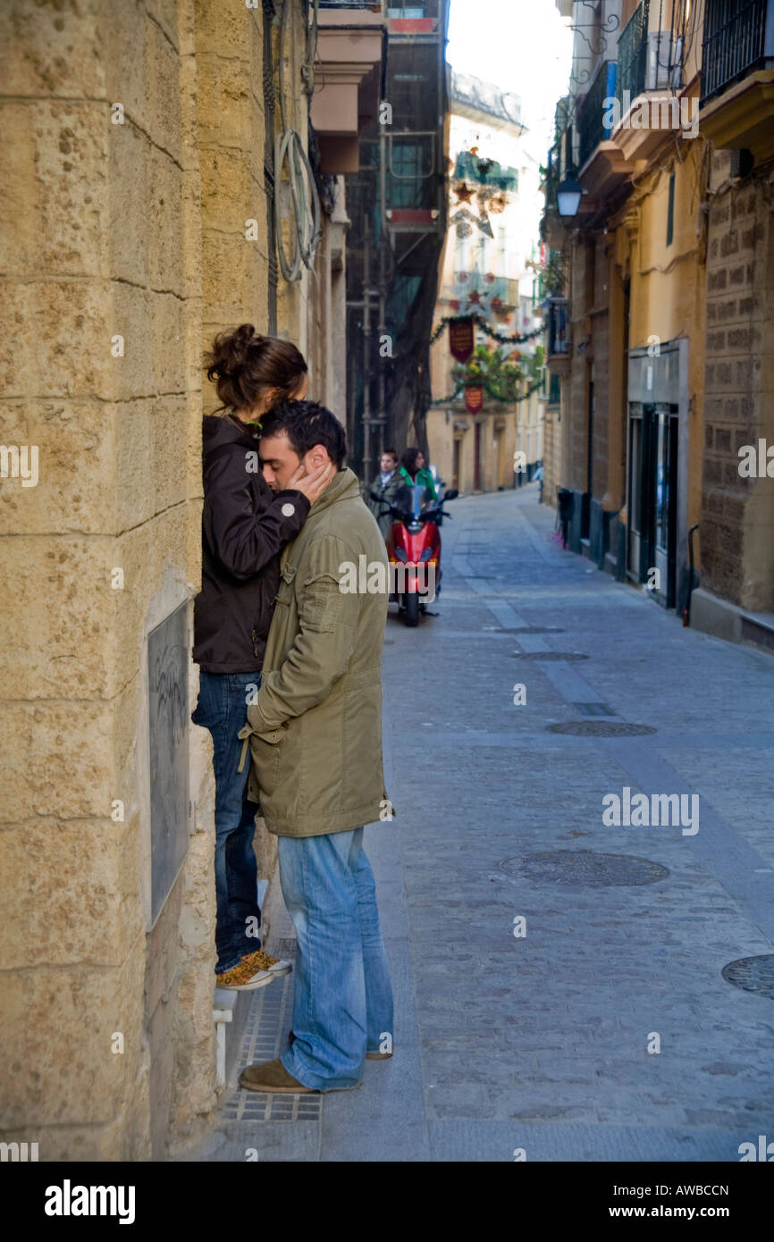 Un joven recibe un abrazo de su novia en una calle lateral en Cádiz Foto de stock