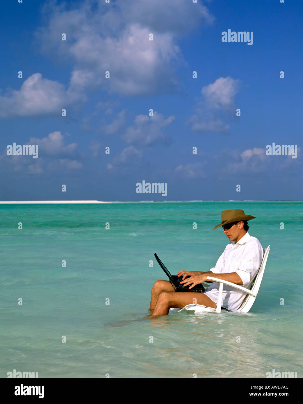 Joven con laptop sentado en la tumbona, de trabajo y de descanso, las vacaciones y el estrés, Maldivas, Océano Índico Foto de stock