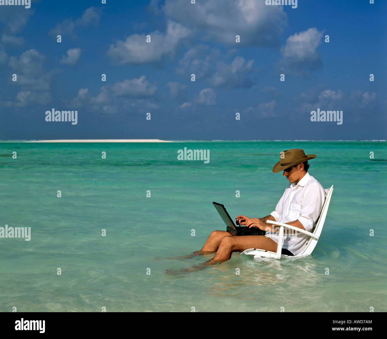 Joven con laptop sentado en la tumbona, de trabajo y de descanso, las vacaciones y el estrés, Maldivas, Océano Índico Foto de stock