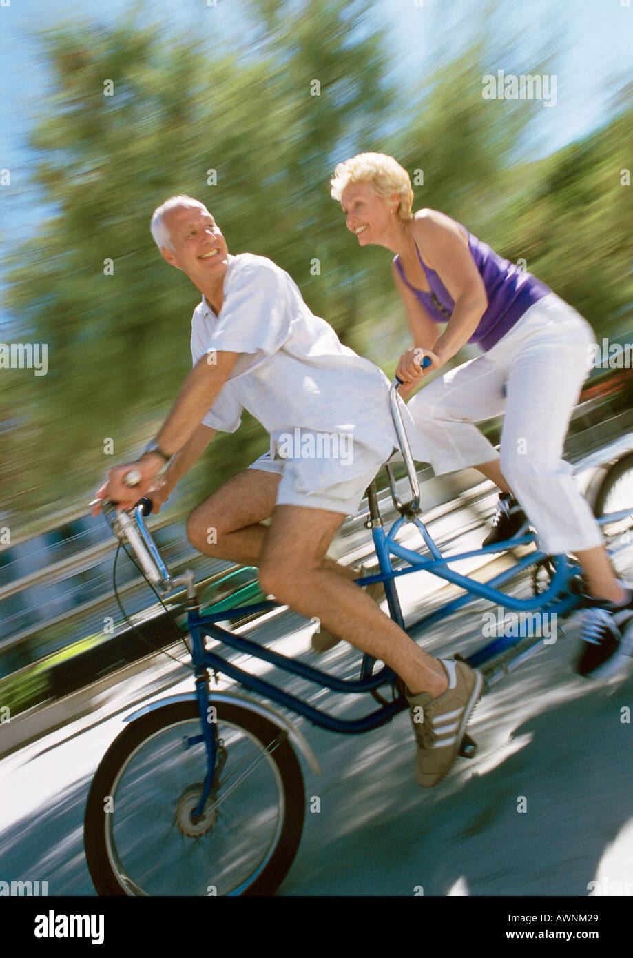Hombre y mujer madura cabalgando juntos en bicicleta tándem, vista lateral,  borrosa Fotografía de stock - Alamy