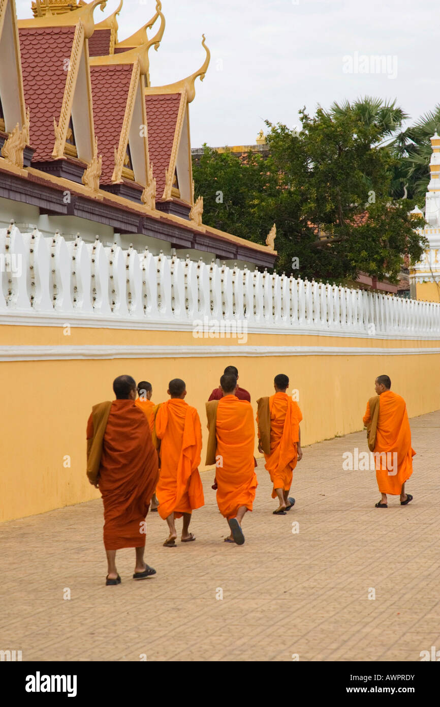 Los monjes budistas vestidos de naranja batas caminar a lo largo de la pared del Palacio Real, en Phnom Penh, Camboya Foto de stock