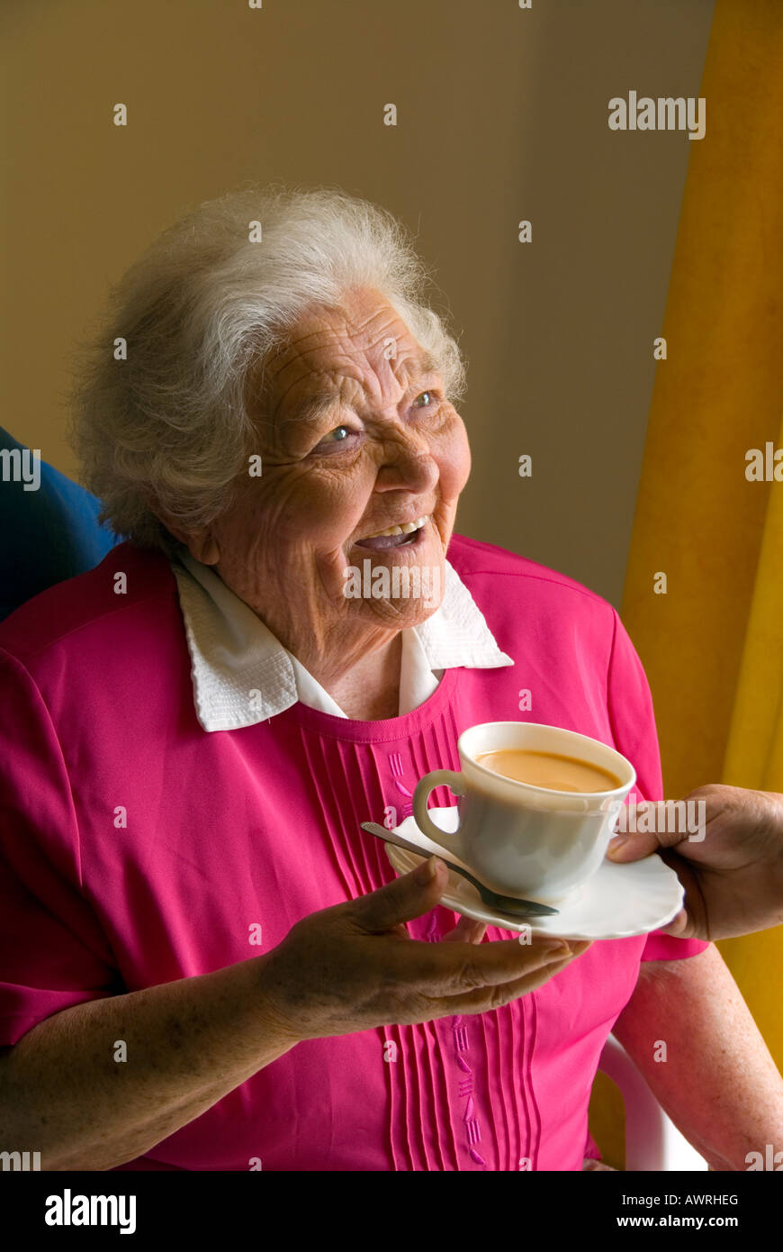 Cuidado cuidar ancianos feliz Tea Room senior INSIDEHappy vieja anciana recibe una taza de té del cuidador acompañante Foto de stock