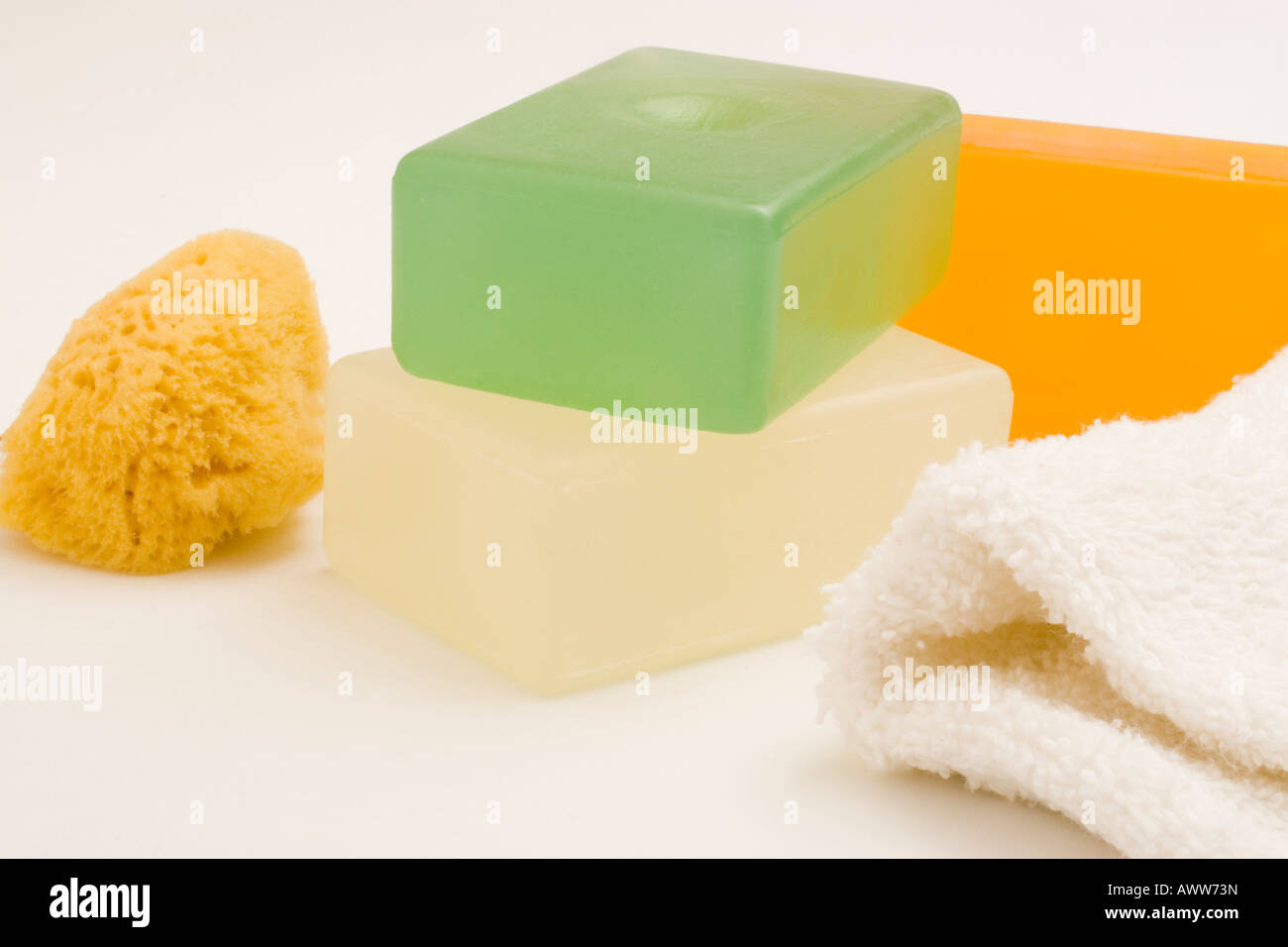 Tres barras de jabón de glicerina transparente de color verde y ámbar claro  y evidente junto con una pequeña esponja y tela blanca Fotografía de stock  - Alamy