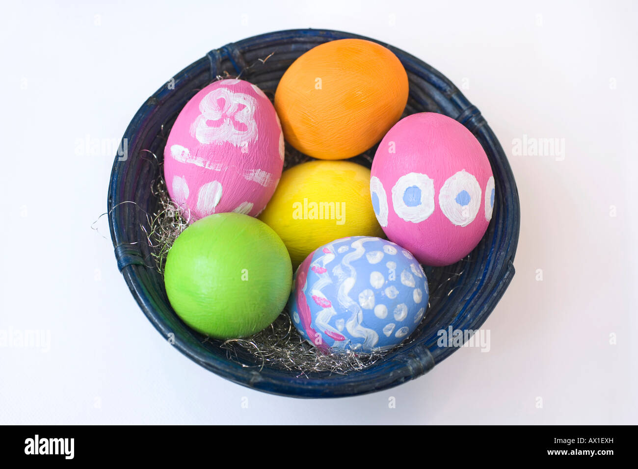 Los huevos de Pascua pintados a mano en un recipiente de bambú azul Foto de stock