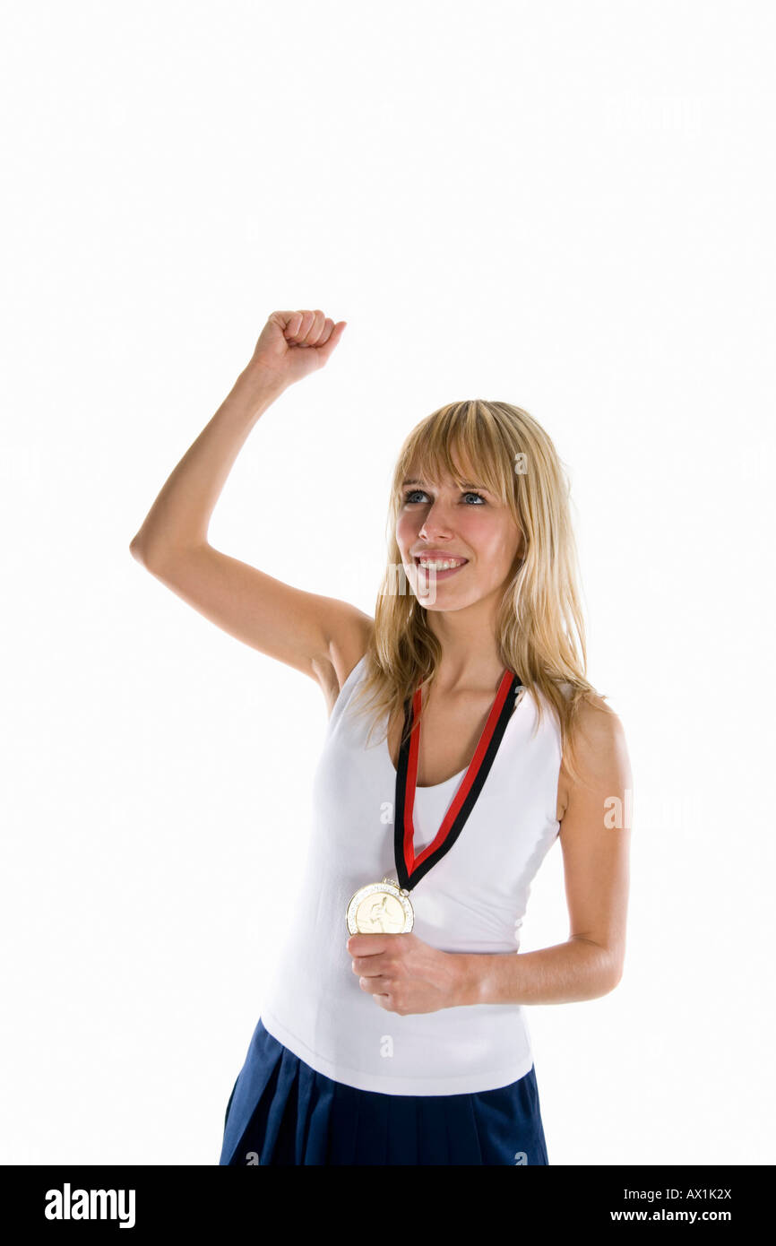 Una mujer que sostiene una medalla de oro y elevando su puño en la celebración Foto de stock