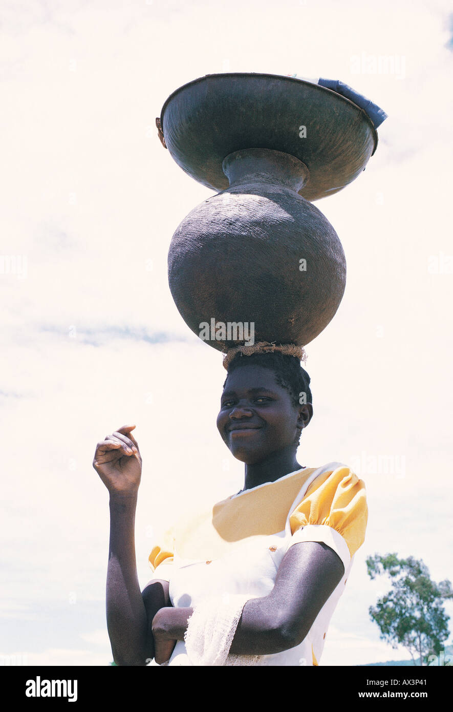 Luo mujer llevando un plato metálico y una olla de barro sobre su cabeza Nyanza del sur en el oeste de Kenia, África Oriental Foto de stock