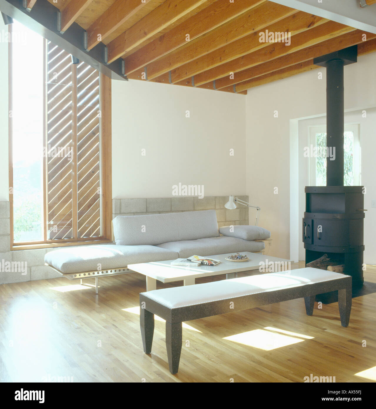 Taburete moderno sofá gris y arquitectónico en salón con estufa de hierro  negro suave y techos con vigas de madera Fotografía de stock - Alamy
