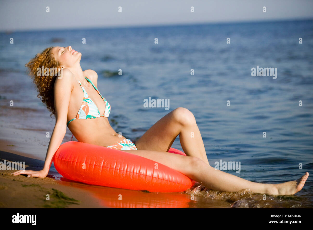 Mujer joven en la playa con neumáticos de flotación Foto de stock