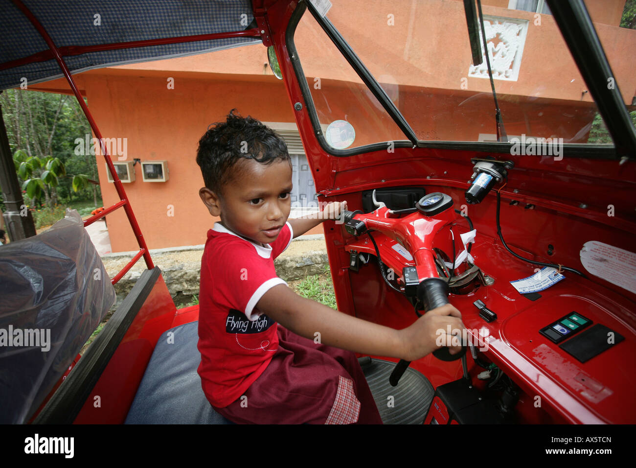 Pequeño muchacho sentado al volante de un tuk-tuk en Hanwella, Sri Lanka, el sur de Asia Foto de stock