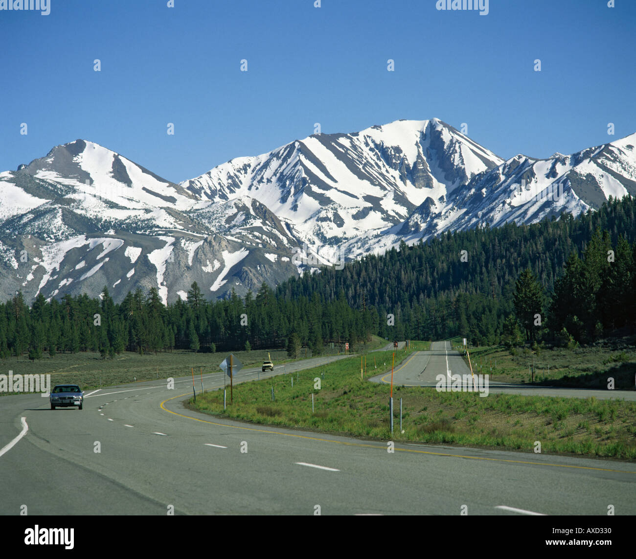 El automovilismo en la Highway 395 en frente a los picos nevados de las montañas de la Sierra Nevada cerca de Mammoth Lakes, California U S A Foto de stock